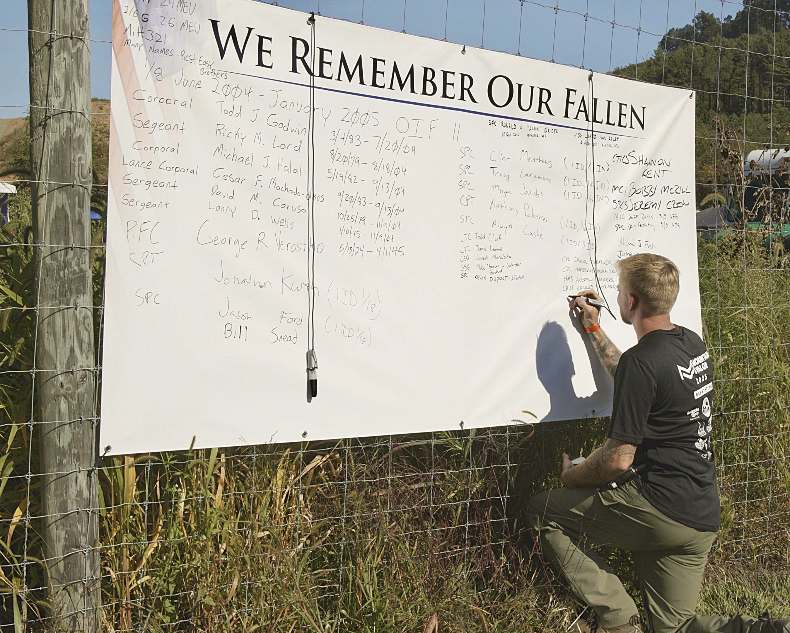 Veteran writing names on the We Remember Our Fallen board at Mountain Valor Fest